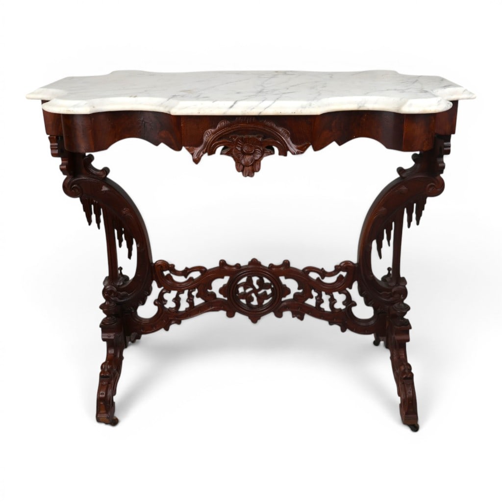 Gothic Revival Mahogany Marble-Top Table: Origin: American, probably New YorkDate: Circa 1860-1875Period/Style: Gothic RevivalMaterials: Mahogany and flame mahogany veneer, white marble, and metal castersForm: Parlor or center tableDescriptio