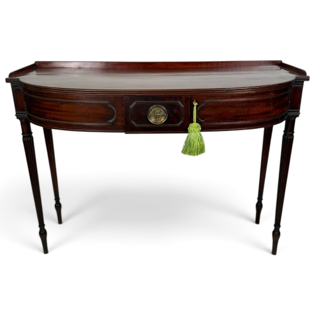 English Regency Mahogany Bowfront Serving Table, Circa 1810-1820: Origin: England. Date: Circa 1810-1820. Period/Style: Regency. Materials: Figured mahogany, mahogany veneer, oak secondary wood, and brass. Form: Bowfront serving table. Description: A refined