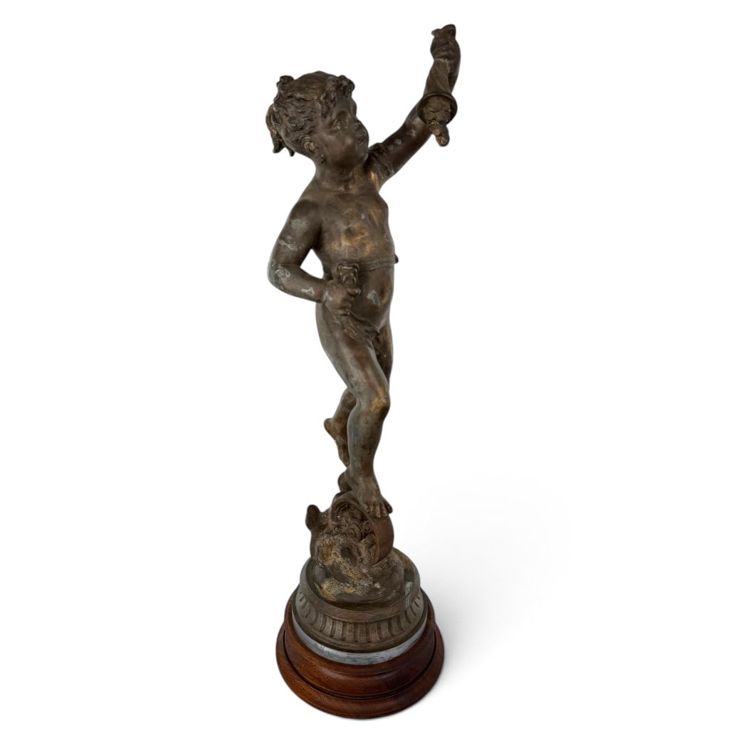 Bronze Boy on Wooden Wheel: Date: Circa 1900-1930 Materials: Patinated bronze, wood, and metal fasteners Form: Figural sculpture Description: A decorative patinated bronze sculpture modeled as a youthful boy posed upon a large
