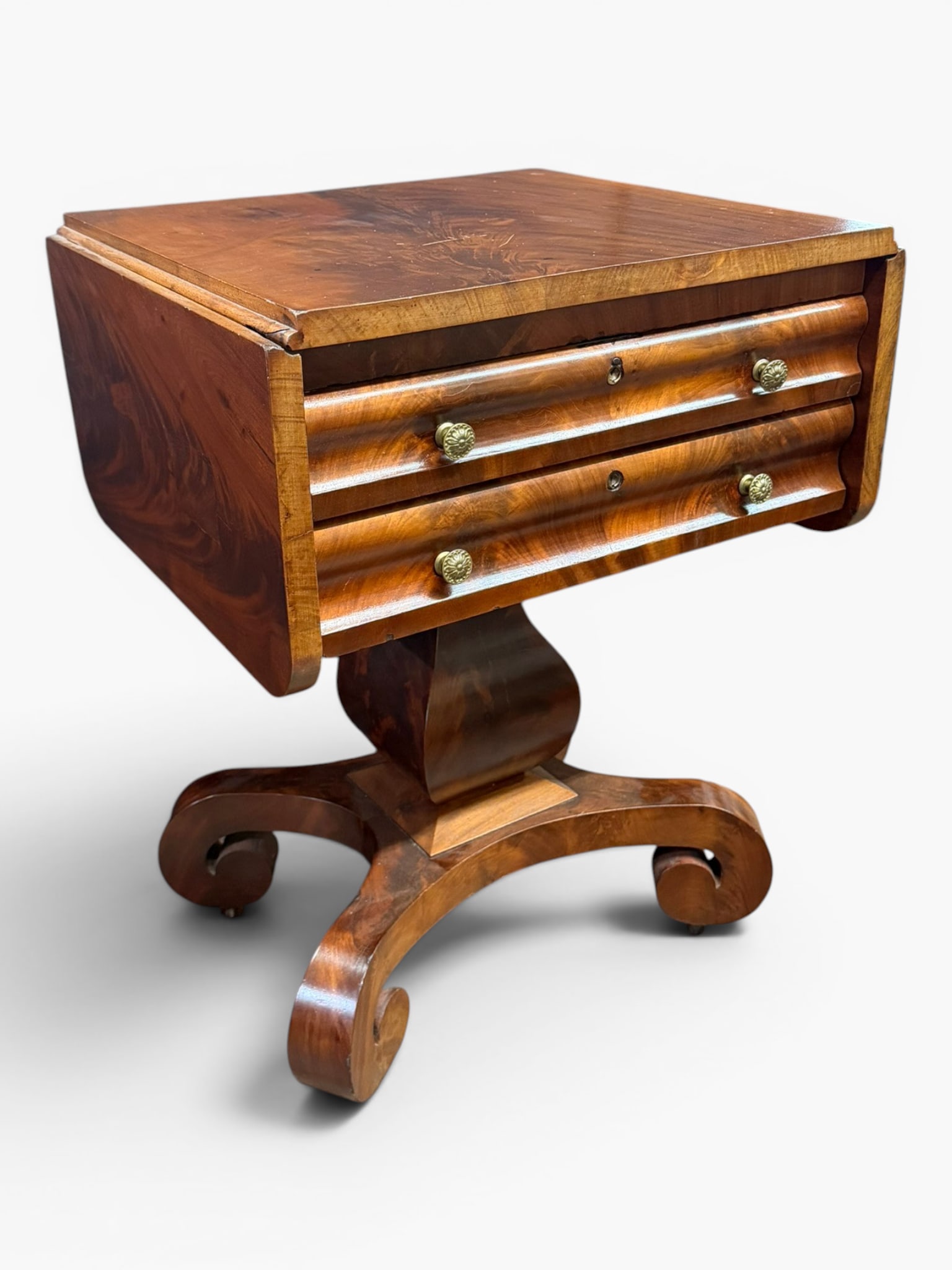American Empire Mahogany Work Table: Origin: American Date: Circa 1830-1845 Period/Style: American Empire Materials: Mahogany and mahogany veneers, secondary woods, and brass hardware Form: Drop-leaf work or sewing table Description: An