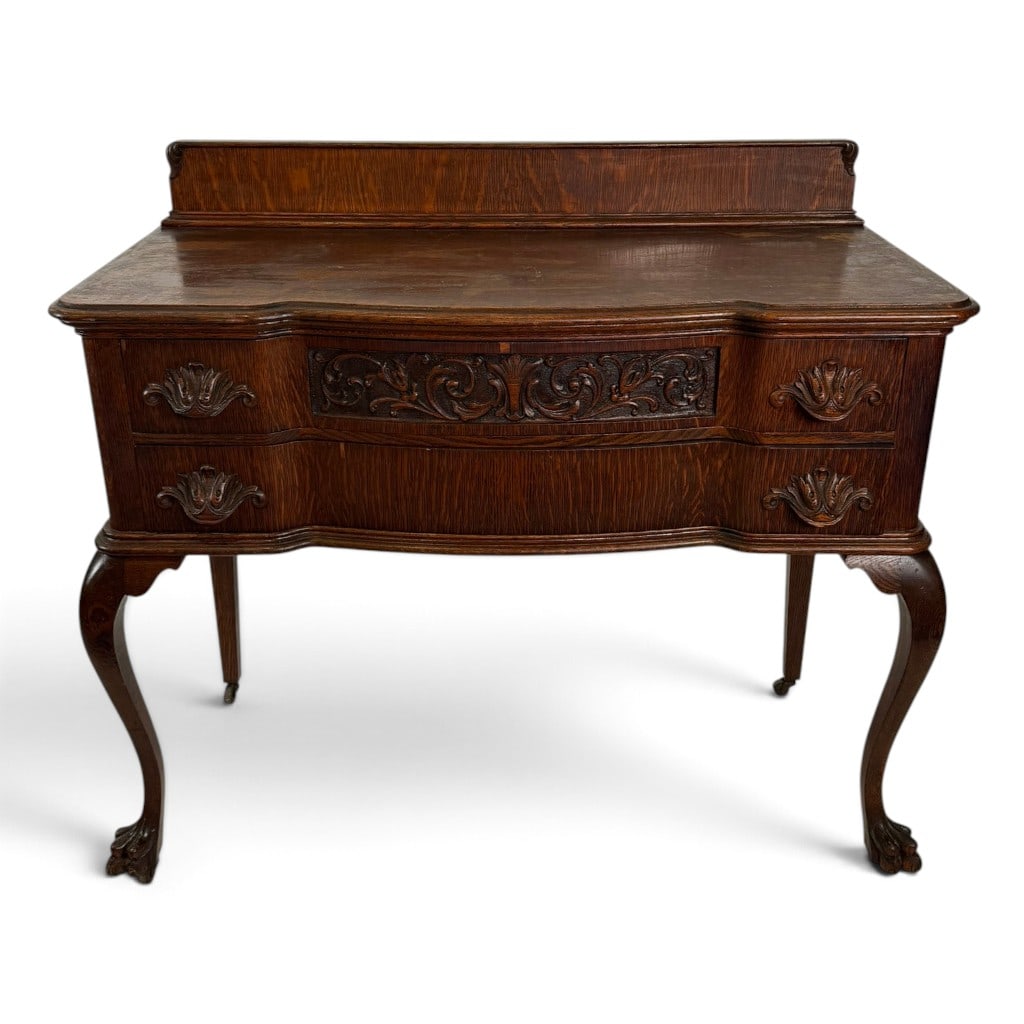 American Carved Quarter-Sawn Oak Server, c. 1900-1915: Origin: Probably United States Date: Circa 1900-1915 Period/Style: Late Victorian, Queen Anne Revival Materials: Quarter-sawn oak, mixed secondary woods, and metal casters Form: Two-drawer serving