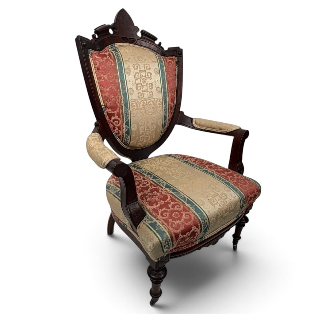 Eastlake Walnut Shield Back Armchair: Origin: American Date: Circa 1875-1890 Period/Style: Victorian, Eastlake with Gothic Revival influence Materials: Walnut, mixed secondary woods, later woven upholstery, brass and metal casters, and