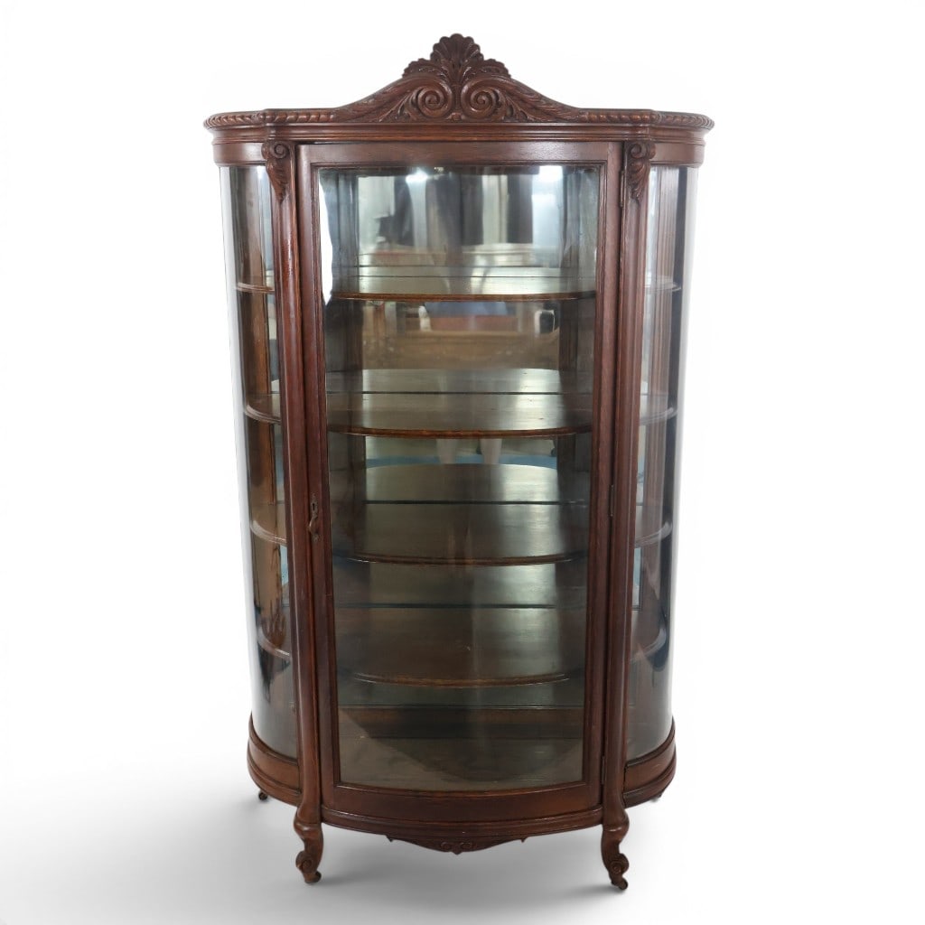 Victorian Curved-Glass China Cabinet: Origin: American Date: Circa 1890-1910 Period/Style: Late Victorian, Rococo Revival Materials: Mahogany and mahogany veneer, curved and flat glass, mirror glass, and mixed secondary woods Form: