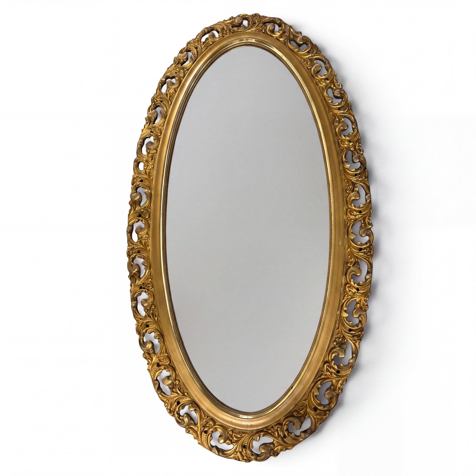 Victorian-Style Gilt Composition Oval Mirror: Date: Early 20th century Period/Style: Victorian and Rococo Revival Materials: Gilt composition and wood, mirror glass, and paperboard backing Form: Oval wall mirror Description: Large oval wall mirro