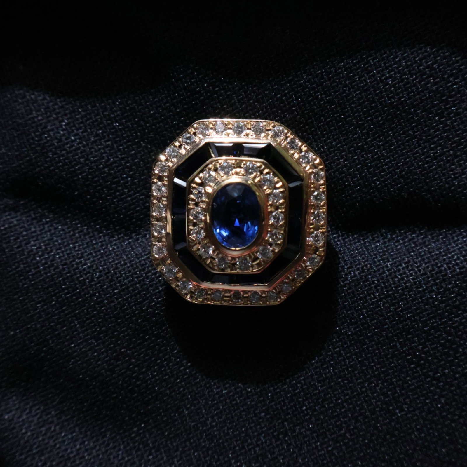 18K Sapphire and Diamond Ring: Date: Late 20th to early 21st century Materials: 18K yellow gold, sapphires, and diamonds Form: Ring Description: An 18K yellow gold cocktail ring set with a central blue sapphire and additional
