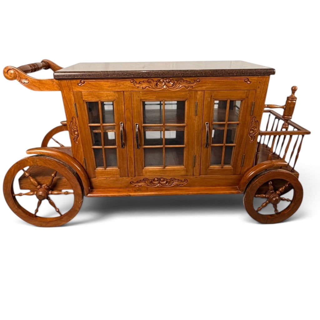 Carved Wood Carriage-Form Bar Cart: Date: Late 20th century Period/Style: Victorian Revival Materials: Carved and turned hardwood, granite, glass, and metal hardware Form: Carriage-form bar cabinet and serving cart Description: Late