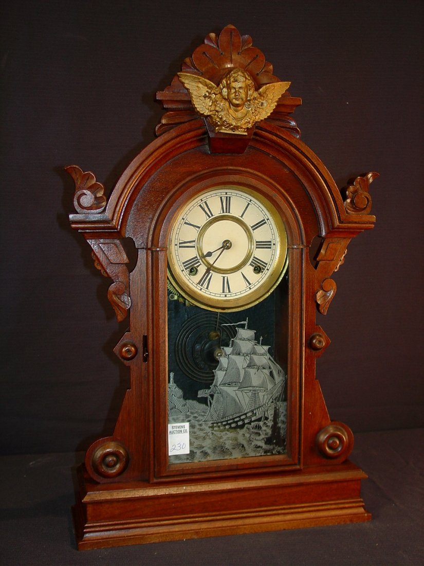 230: Walnut Victorian kitchen clock with bronze angel: Walnut Victorian kitchen clock with bronze angel on crown by R. Booth, key and pendulum, 24in. T, 14om. W, 4in. D.