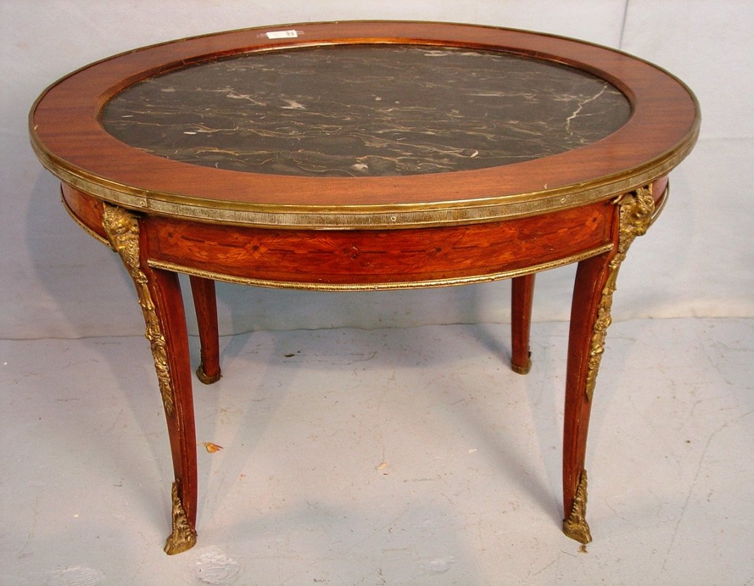 French Oval walnut coffee table with black and gold: French Oval walnut coffee table with black and gold marble top trimmed with bronze goat heads, ca 1900 - 21 in. T x 30 in. L x 23 in. depth