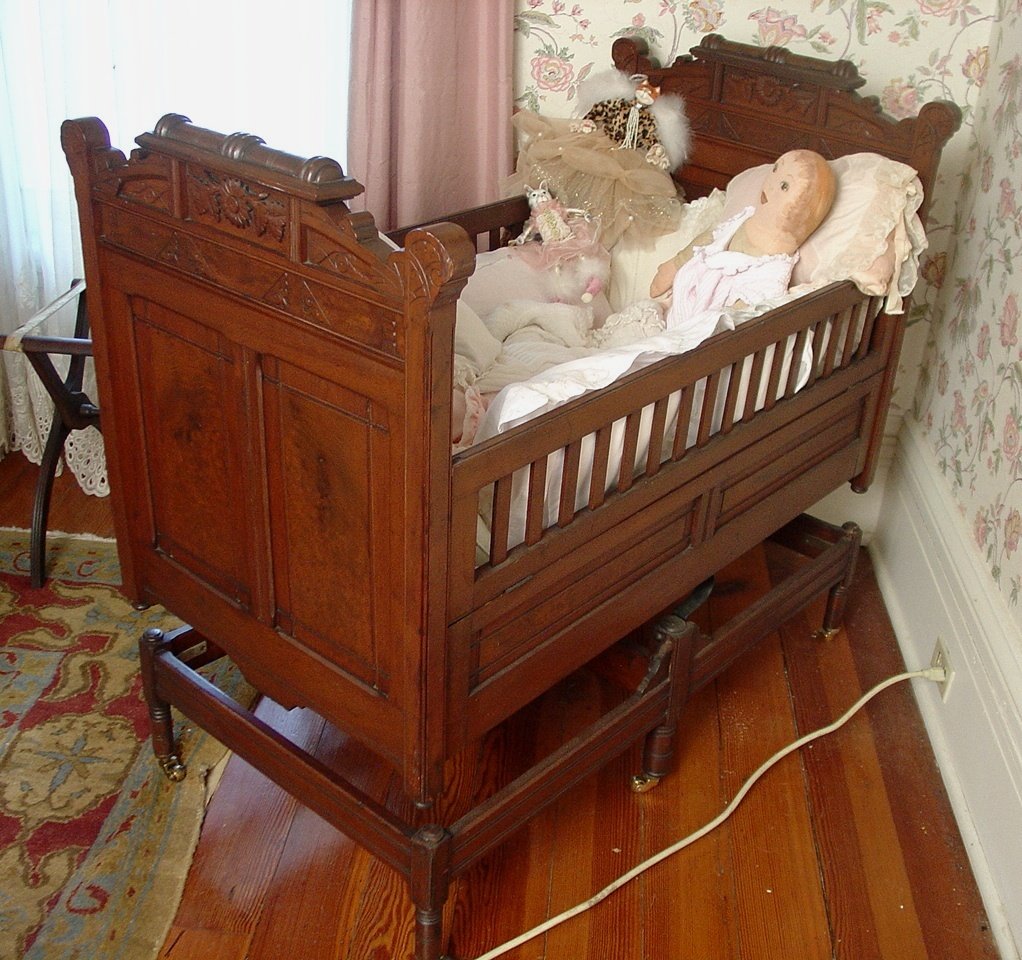 Walnut Victorian baby bed with trim and great carving,: Walnut Victorian baby bed with trim and great carving, bed rocks from end to end, 42in. T, 42in. L, 24in. W, ca. 1875.