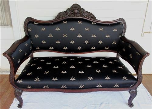 Mahogany heavily carved loveseat: Mahogany heavily carved loveseat with black dragon fly upholstery, 43 in. T, 53 in. W, 23 in. D.