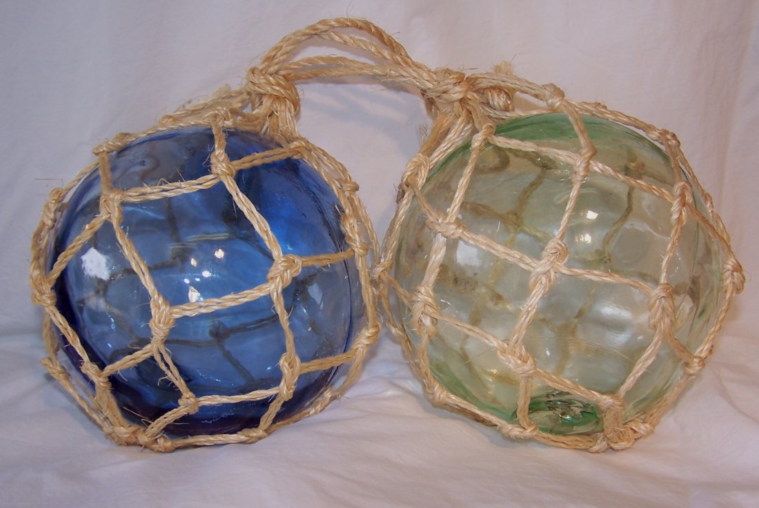 Pair of Glass Japanese Fishing Floats: This is a pair of glass japanese fishing floats with the rope holders. One is blue glass and the other green. They are approximately 6" in diamter.