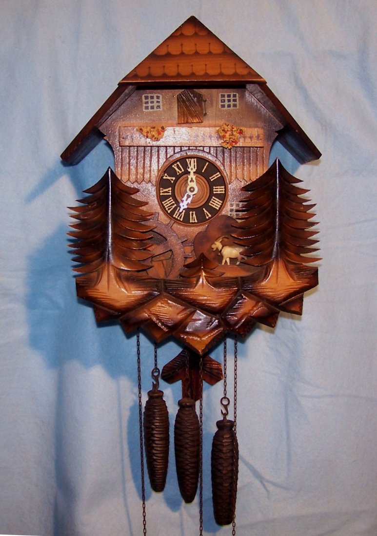 German Mountain Cabin Musical, Time and Strike Cuckoo: This is a vintage Cuckoo Clock. It was made sometime around 1988. It was made in Germany and portrays a lovely Mountain Cabin in the Woods. It has a cut goat in the front and a Waterwheel that turns w