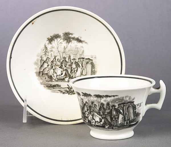 English Creamware Cup and Saucer, c. 1810-20: An English Neo-Classical Creamware Cup and Saucer, c. 1810-20, each with black transfer-printed scene of William Penn's treaty with the Indians, after Benjamin West's original painting, note: two crac