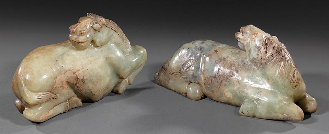 Two Chinese Carved Soapstone Recumbent Horses: Two Chinese Carved Celadon and Russet Soapstone Recumbent Horses, 20th c., h. 5 3/4 in. and 4 7/8 in., l. 10 1/4 in. and 11 1/2 in., stands, overall h. 6 5/8 in. and 6 1/4 in. Provenance: Estates of M