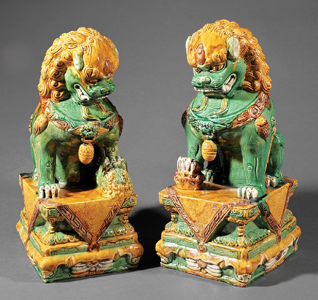 Chinese Green, Ochre Glazed Pottery Budhist Lions: Pair of Chinese Green and Ochre Glazed Pottery Buddhist Lions, each modeled seated on a draped rectangular plinth, the male with its right paw resting on a brocade ball and the female with a cub, h. 1