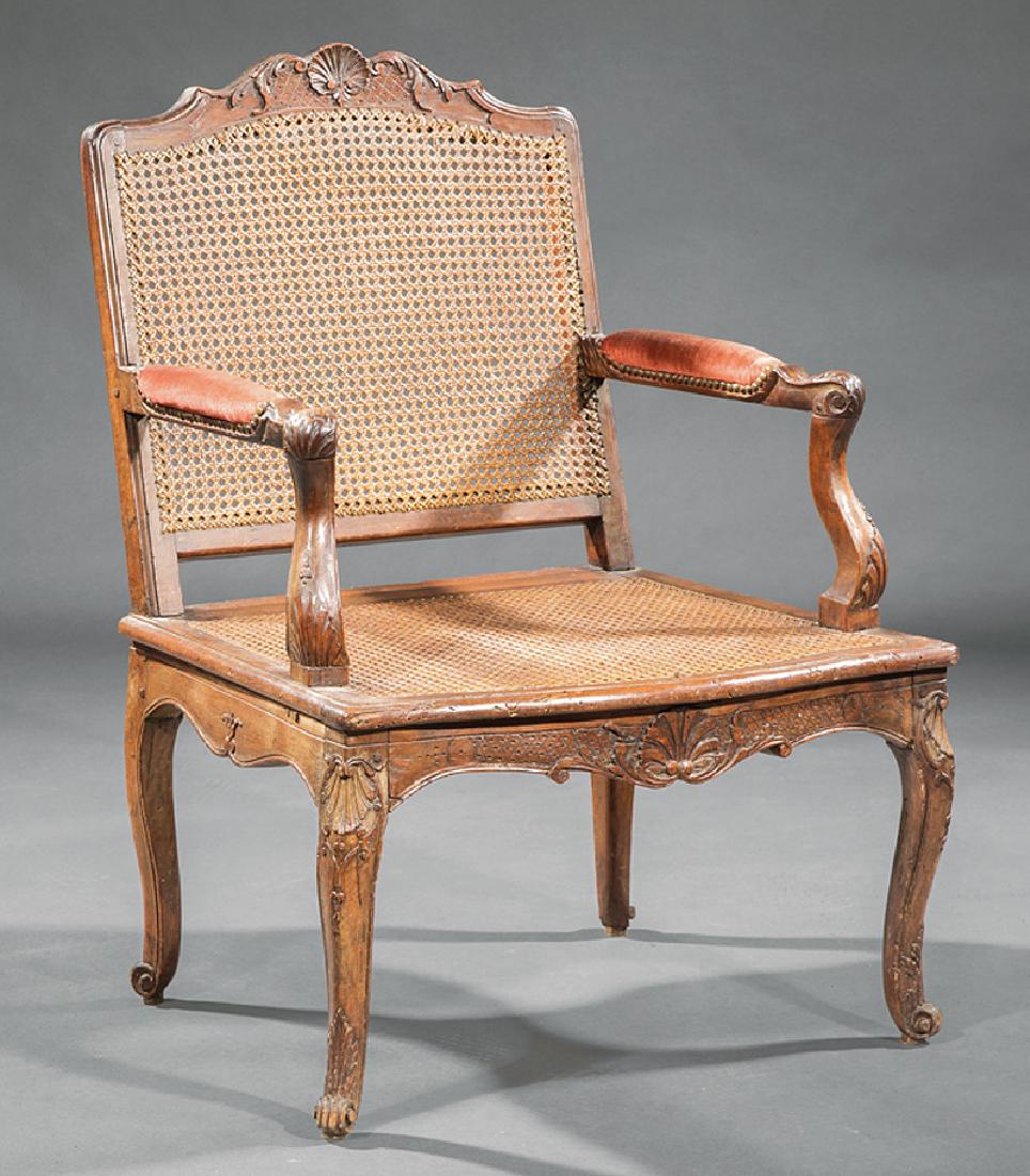 Regence Carved Fruitwood Fauteuil: Regence Carved Fruitwood Fauteuil, likely 18th c., serpentine crest rail centered by a carved shell, caned back and seat, foliate scrolled uprights, conforming seat rail, cabriole legs, scrolled toes,