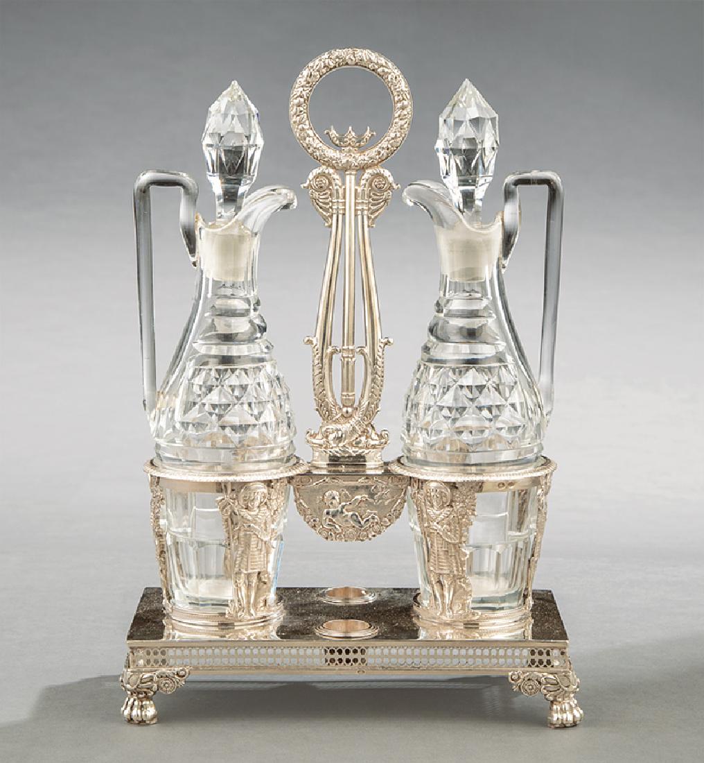 French Silver and Cut Crystal Cruet Stand: French First Standard Silver and Cut Crystal Cruet Stand in the Empire Taste, early 19th c., dolphin and ring handle, figural bottle supports, paw feet with anthemion brackets, diamond faceted cruets 