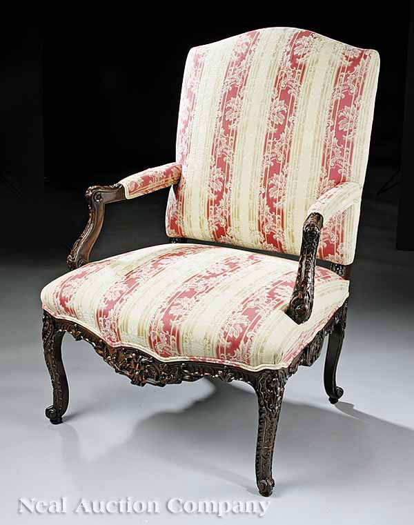 George III-Style Carved Walnut Library Armchair: A George III-Style Carved Walnut Library Armchair , c. 1900, in the manner of Thomas Chippendale, having an arched crest, floral-carved arms and seat rail on cabriole legs with scrolled feet, upholste