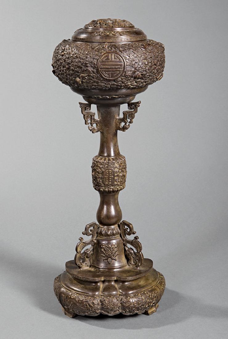 Chinese Patinated Bronze Covered Hat Stand: Chinese Patinated Bronze Covered Hat Stand, pierced cover, globular top and mid-section relief-cast with bats amid cloud scrolls, standard with archaistic zoomorphic flanges, footed lobed base with ap