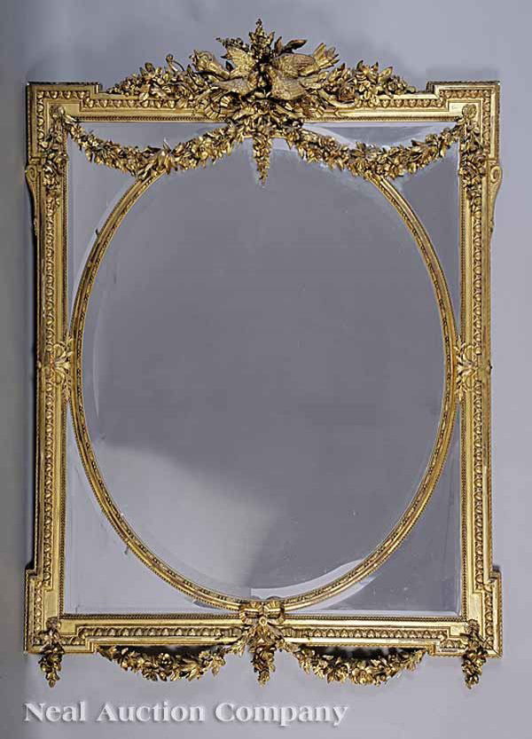 Carved Giltwood Overmantel Mirror: An Antique Carved Giltwood Overmantel Mirror , 19th c., in the Adam taste, the floral crest centered with doves, quiver and torch, the egg and dart frame blocked at the corners, oval beaded inner fram