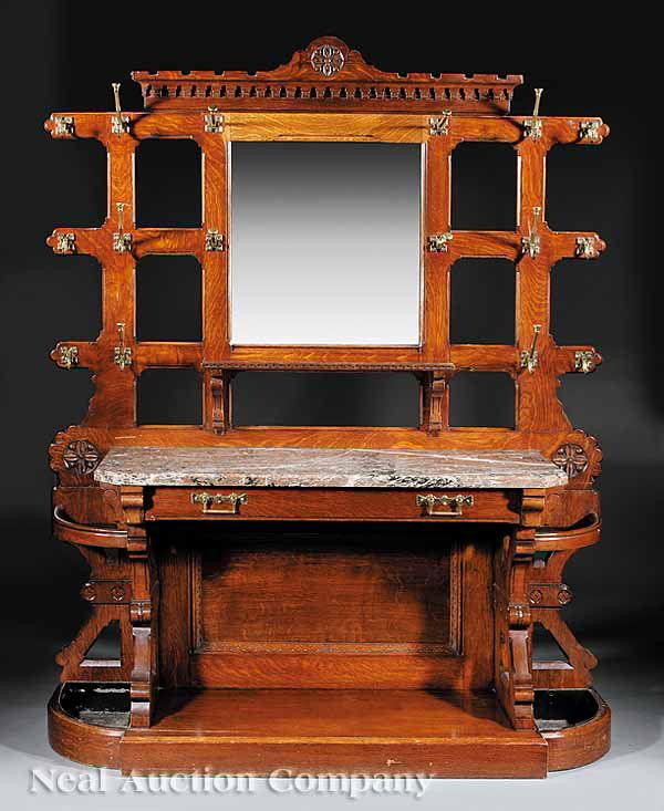 Scottish Arts and Crafts Carved Oak Hall Stand: A Scottish Arts and Crafts Carved Oak Hall Stand , c. 1875, stamped "John Taylor & Sons, Manufacturer, Edinburgh", a dentillated cornice above a square mirror plate flanked by stiles mounted with bras