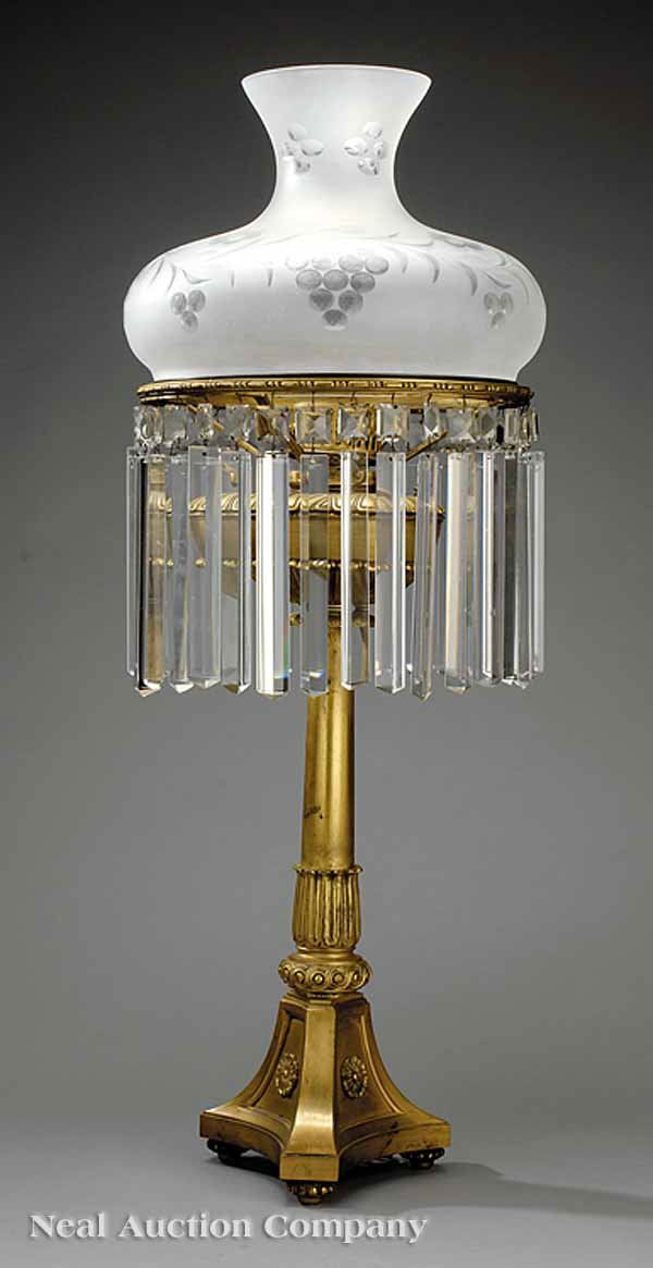American Brass Sinumbra Lamp: An American Brass Sinumbra Lamp in the Classical Taste, 19th c., rosette-decorated triangular base supporting a clumnar standard, prism-hung with a floral and etched glass shade, now wired for electri
