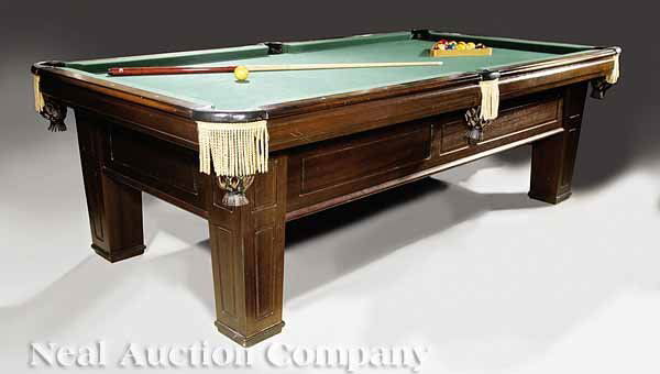 Vintage Moderne Mahogany Billiard Table Brunswick: A Vintage Moderne Mahogany Billiard Table, c. 1920, Brunswick, the slate top of standard size, green felt playing surface, with molded paneled skirt and square legs, with one pool cue, a rack and ball