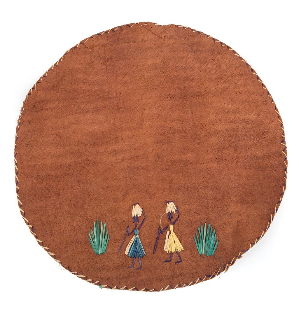 African Grass Embellished Leather Pillow Cover: African Grass Embellished Leather Pillow Cover , design with two women carying baskets, blue, green and neutral dyed grass, dia. 11 1/2 in. Condition: very good; small crease to one side Provenance: P