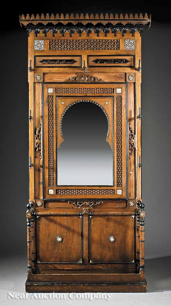 Inlaid, Parcel Ebonized Hardwood Hall Stand: A Moroccan Inlaid and Parcel Ebonized Hardwood Hall Stand, late 19th c., crenellated cornice, bone-inlaid tiles above panels incised with Arabic script, Moorish arch, shaped mirror plate, umbrella sta