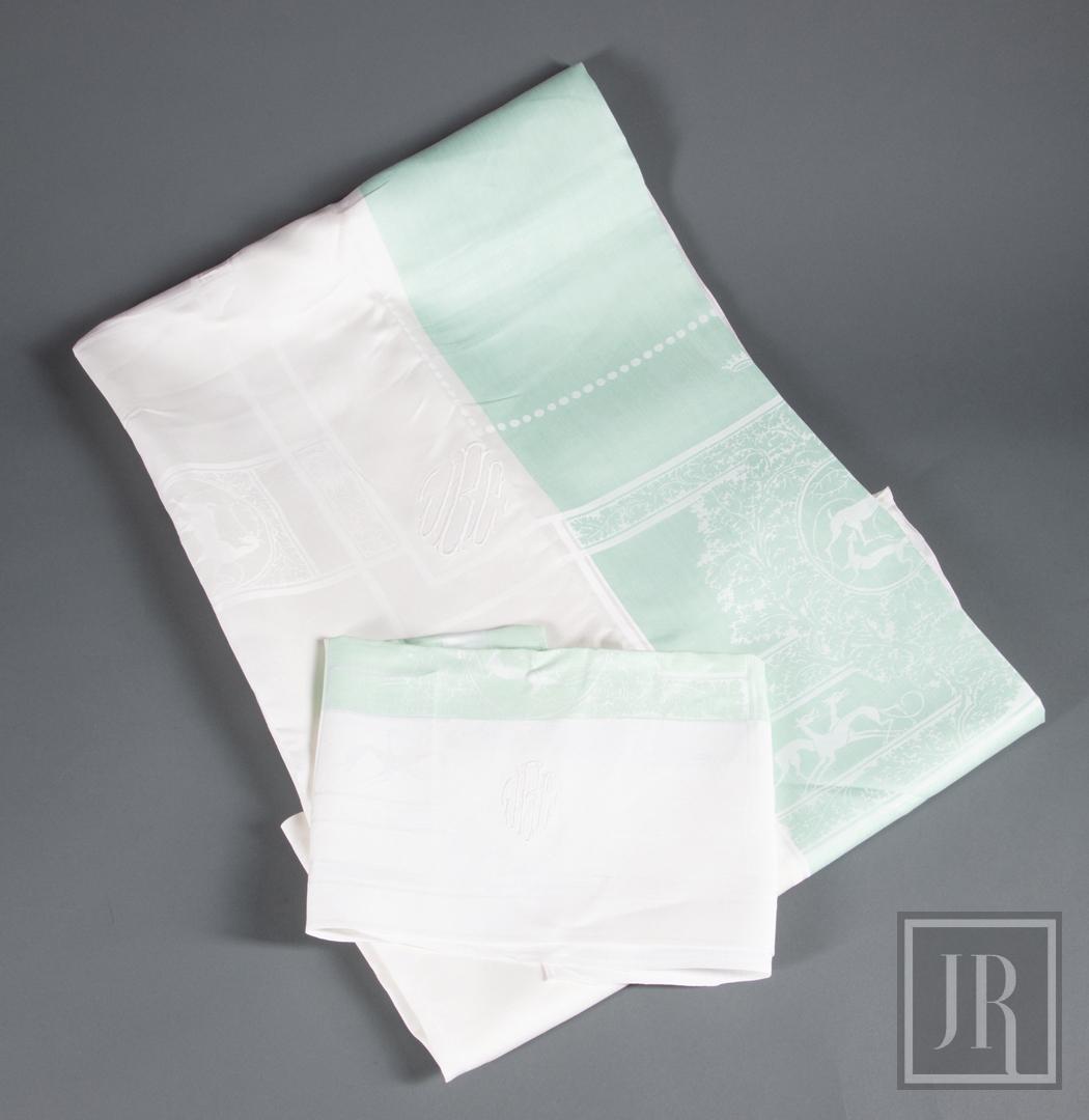 White and Green Linen Damask Tablecloth/Napkins: White and Green Linen Damask Tablecloth with 12 Matching Napkins , deer motif with "JCB" monogram, tablecloth 119 in. x 140 in. Note: small mend to edge of tablecloth . Provenance: Estate of Julia Eva
