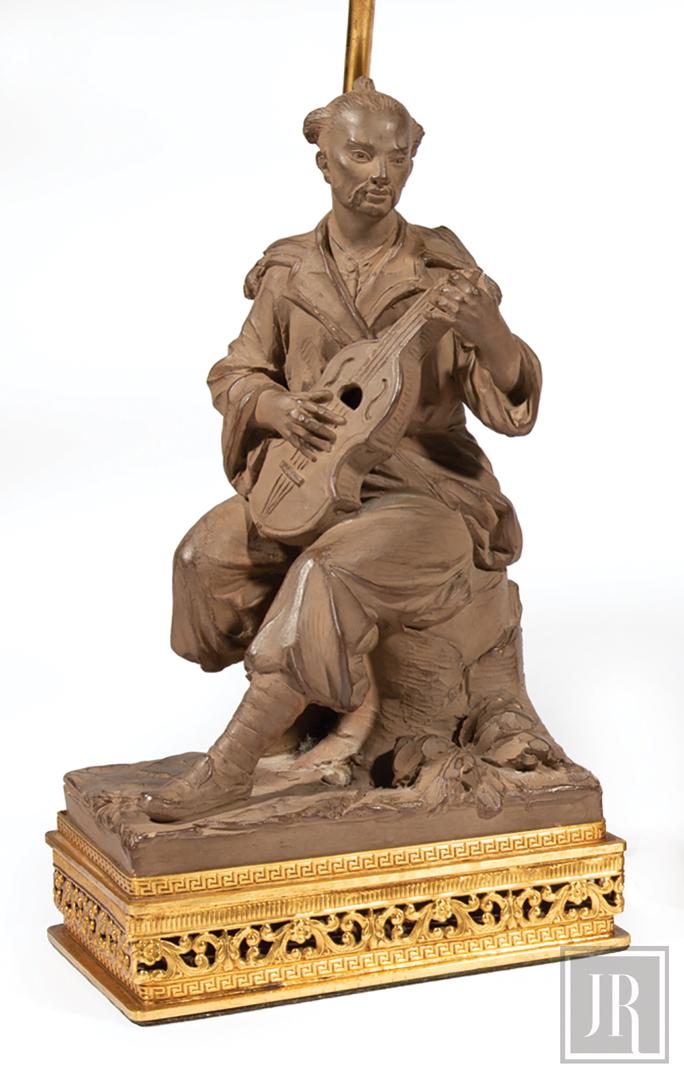 French Patinated Terracotta, Bronze Figural Lamp: French Patinated Terracotta and Bronze Figural Lamp , stamped "Made in France", figure playing guitar, h. (to finial) 24 5/8 in., note: loss to handle of guitar Provenance: Estate of Julia Evans Reed.