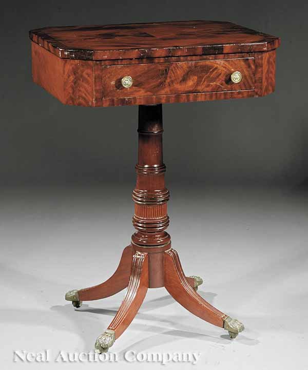 American Classical Carved Mahogany Work Table: An American Classical Carved Mahogany Work Table , early 19th c., bookmatched top with canted corners, single drawer, tapered ring-turned and reeded shaft, reeded saber legs ending in brass paw feet, 