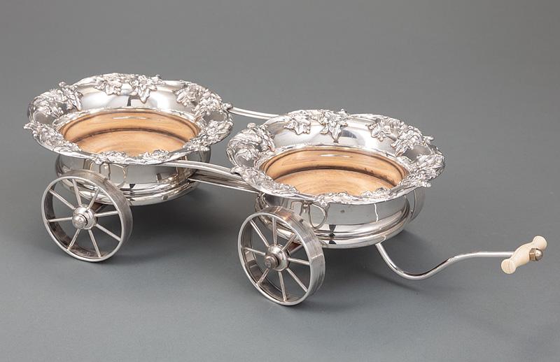 English Silverplate Wagon-Form Wine Trolley: Antique English Silverplate Wagon-Form Wine Trolley , 19th c., fitted with two wine coasters, each with turned hardwood bottom and button, floral and acanthus decoration, silver bottom, movable carria