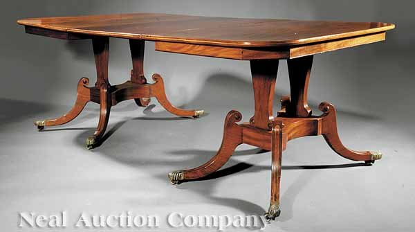 Inlaid Mahogany Pedestal Dining Table: An Antique Regency-Style Inlaid Mahogany Pedestal Dining Table, the rectangular top and plain skirt opening to take one leaf, on trestle pedestal with hipped saber legs, paw cuffs, casters, height 27 