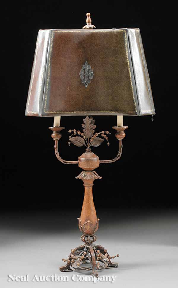 Tôle Peinte, Composition and Leather Table Lamp: A Decorative Tôle Peinte, Composition and Tooled Leather Table Lamp, the foliate decorated shaft issuing two candle arms, height 22 in., width 11 in., depth 8 in