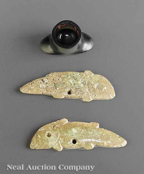 Group of Three Colima Ornaments: A Group of Three Colima Ornaments, c. 300 BC - AD 300, including two jadeite flattened fish form pendants, height 1 5/8 in. and 1 3/4 in., and a black obsidian or jet "hat" form lip plug, height 1 in.