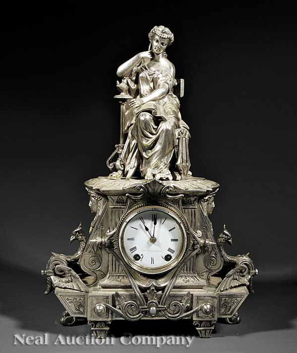 Seth Thomas Sons & Co Metal Figural Mantel Clock: An Antique Silvered Metal Figural Mantel Clock, 19th c., Seth Thomas Sons & Co., New York, the figure sitting on klismos chair, with lyre beside her, porcelain dial flanked by pharaoh masks and phoeni