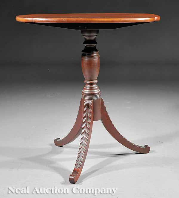 Classical Carved Mahogany Tilt-Top Candlestand: An American Classical Carved Mahogany Tilt-Top Candlestand, early 19th c., in the manner of Duncan Phyfe, New York, the oval top with shaped corners, bold ring and urn-turned support, outswept acanthu