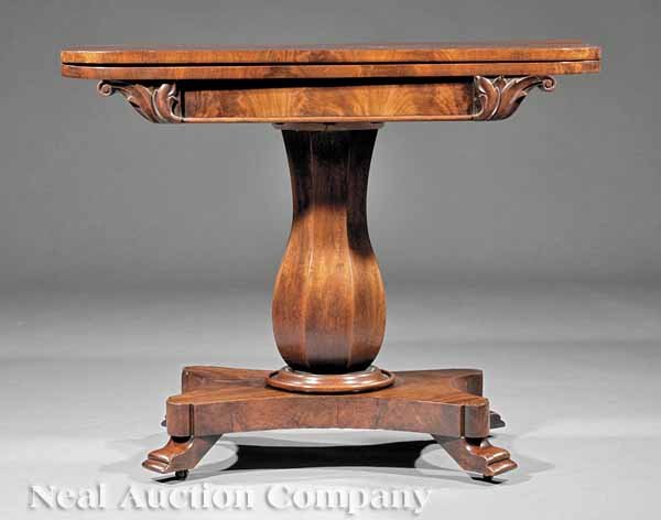 William IV Carved Mahogany Games Table: A William IV Carved Mahogany Games Table, c. 1840, foldover swivel top, skirt with foliate scroll brackets, chamfered stem, incurvate plinth, scroll feet, height 29 in., width 36 in., depth 18 in