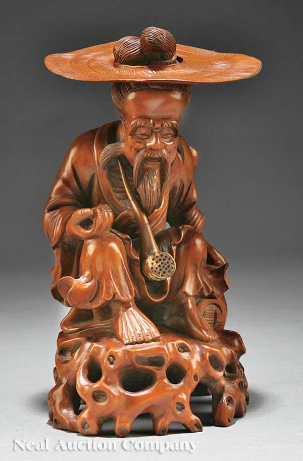 Chinese Carved Wood Figure of an Old Man: A Chinese Carved Wood Figure of an Old Man with a Hat and Pipe, probably 20th c., modeled seated on a naturalistic "stone" base, wearing a removable hat with a satchel at his side and a loose pipe in
