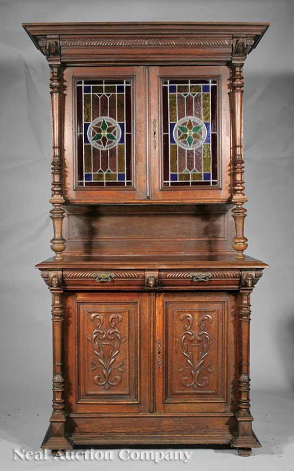 Renaissance Revival Carved Walnut Cabinet: A Continental Renaissance Revival Carved Walnut Cabinet, late 19th c., upper case with a gadrooned cornice and masks at corners, stained glass doors flanked by turned stiles, baluster supports and pan