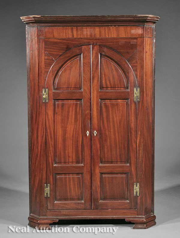Queen Anne Mahogany Corner Cupboard: A Queen Anne Mahogany Corner Cupboard, 18th c., stepped molded cornice, arched raised panel doors enclosing scalloped shelves and small drawers, molded base, ogee bracket feet, height 55 1/2 in., widt