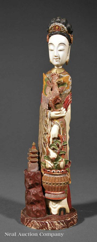 Chinese Polychrome-Decorated Ivory Figure: A Chinese Polychrome-Decorated Ivory Figure of the Immortal Xi Wangmu, the Queen Mother of the West carved carrying a phoenix cradled in one arm and a basket of peaches in the other, standing beside a