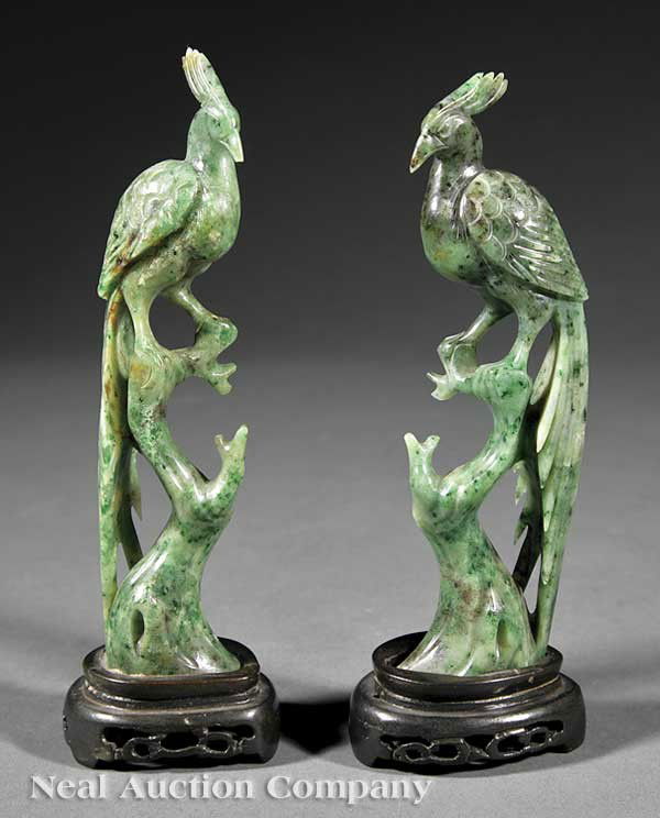 Pair of Chinese Spinach Jade Phoenix Birds: A Pair of Chinese Spinach Jade Phoenix Birds, late 19th c., each mottled green stone carved in mirror image of the other as a noble bird perched on a tall stump, its head turned slightly over its brea