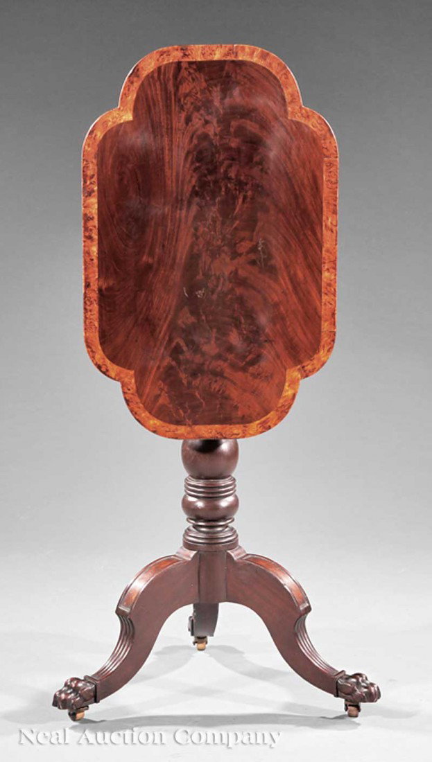 Carved Mahogany, Burl Inlaid Tilt-Top Candlestand: An American Federal Carved Mahogany and Burl Inlaid Tilt-Top Candle Stand, early 19th c., shaped top, baluster support, paneled and reeded legs ending in paw feet, casters, height 30 in., width 25 in.