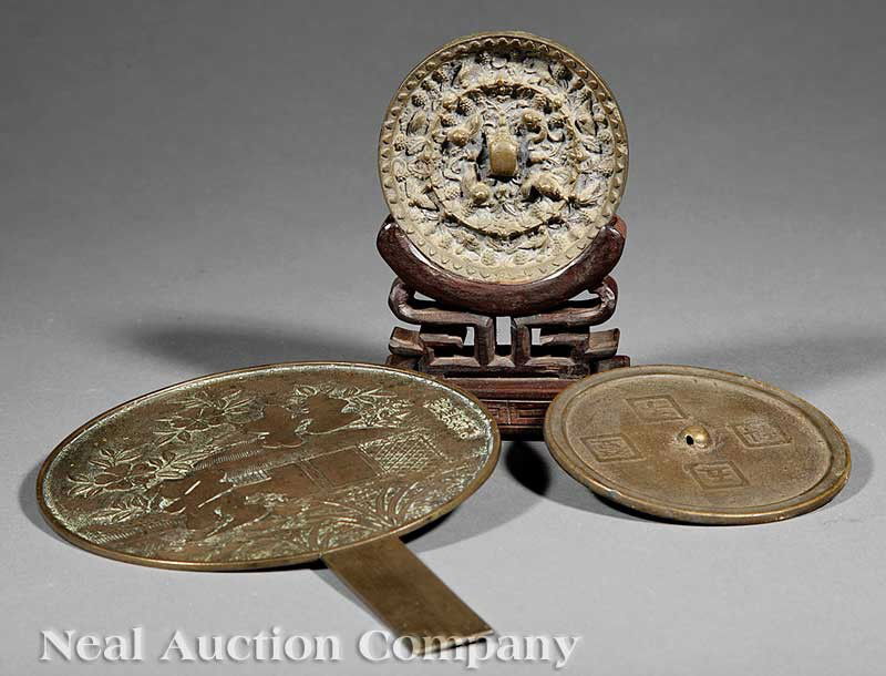 Chinese and Japanese Bronze Mirrors: A Group of Three Antique Chinese and Japanese Bronze Mirrors, including a Chinese Tang style bronze 'Lion and Grapevine' mirror, the central knob formed by a crouching zoomorphic figure surrounded by