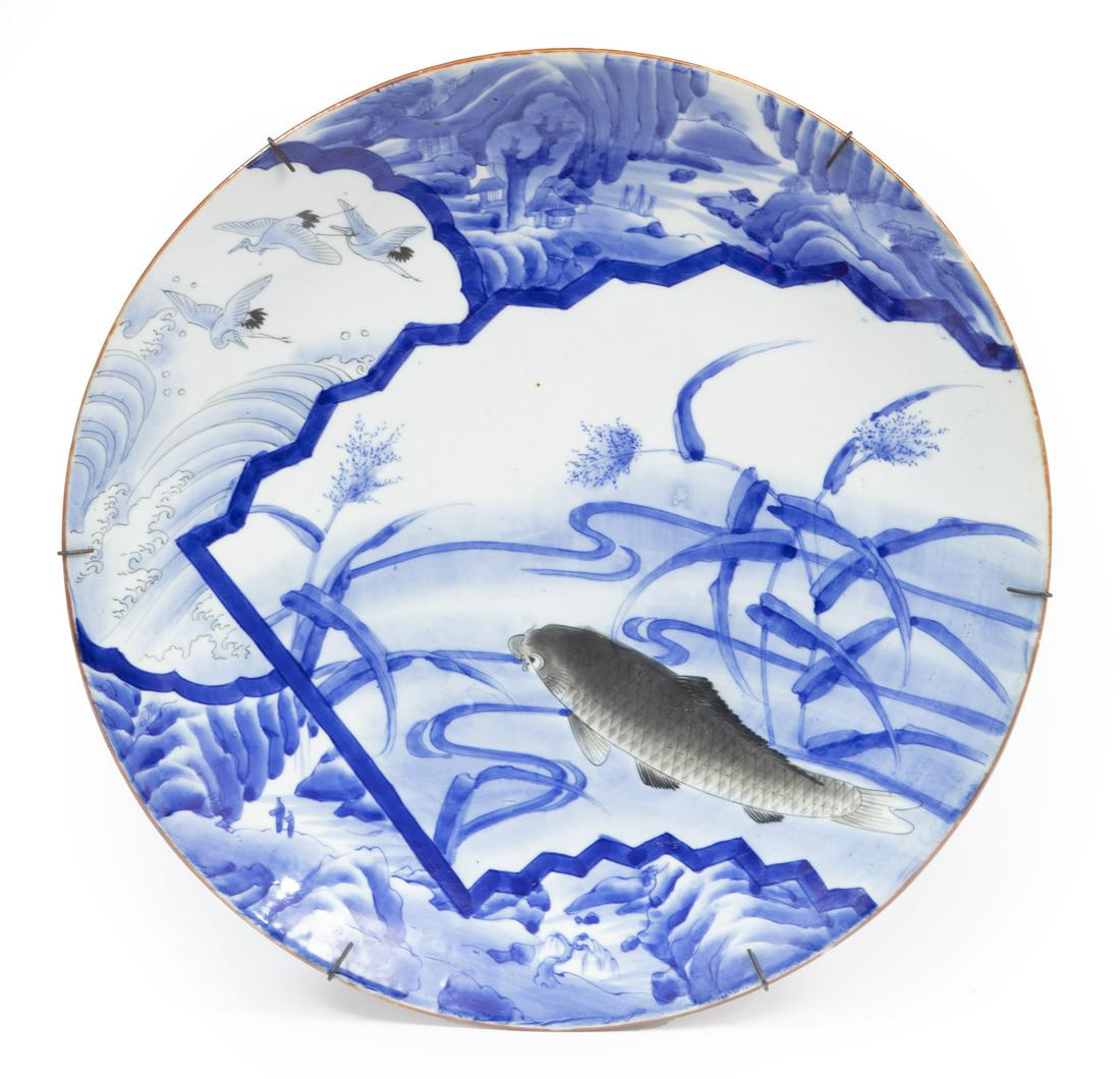 Japanese Grisaille-Decorated Blue and White Porce: Japanese Grisaille-Decorated Blue and White Porcelain Charger, Meiji Period (1868-1912), painted with scenic panels enclosing carp amid water reeds, cranes and breakers, and a waterscape, h. 2 1/2 in.