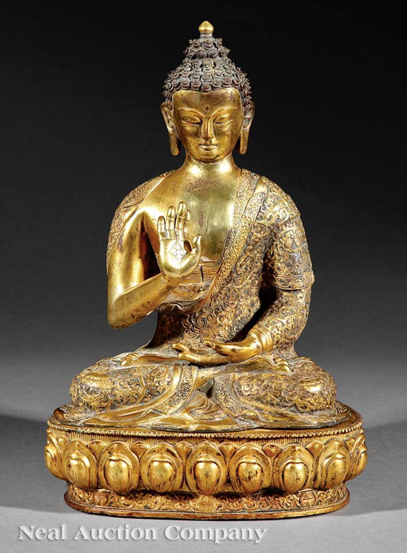 Tibetan Gilt Bronze Figure of Buddha: A Tibetan Gilt Bronze Figure of Buddha, modeled seated upon a separately cast lotus pedestal base in vajrasana baring exposed foot soles, his right hand raised in abhaya mudra and his left held above 