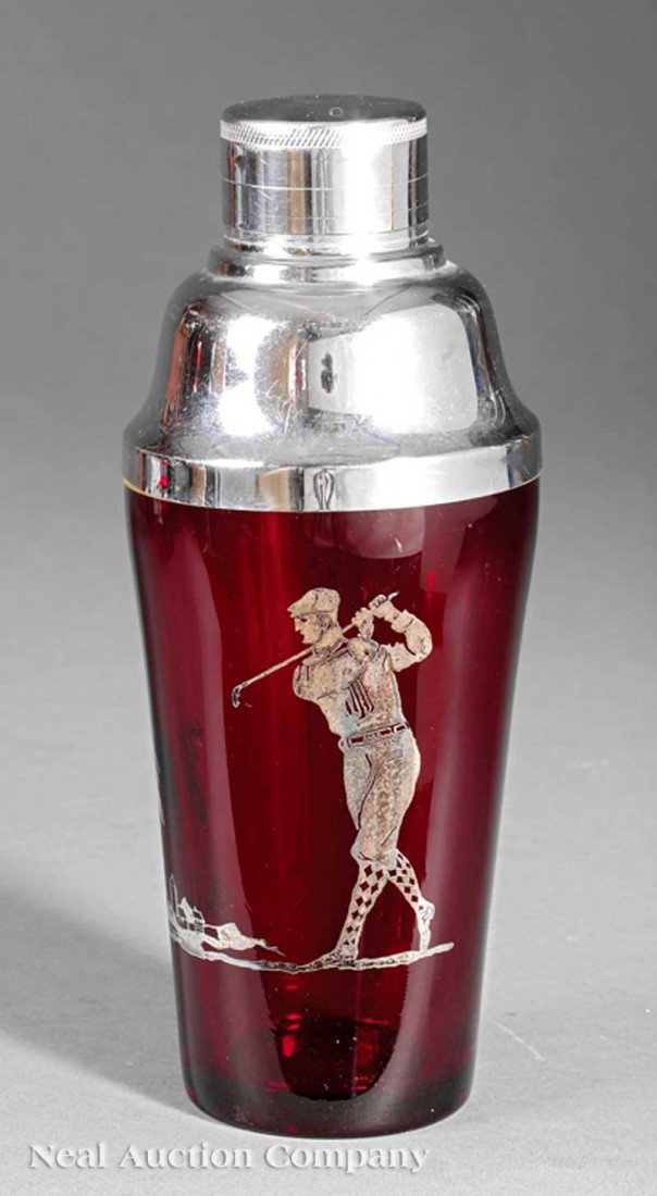 Deco Ruby Glass, Silver-Mounted Cocktail Shaker: An Art Deco Ruby Glass and Silver-Mounted Cocktail Shaker, c. 1920, chrome-plated cap with strainer, the glass with a silverplate scene of a golfer in mid-swing, a palm tree in the distance, height 8 