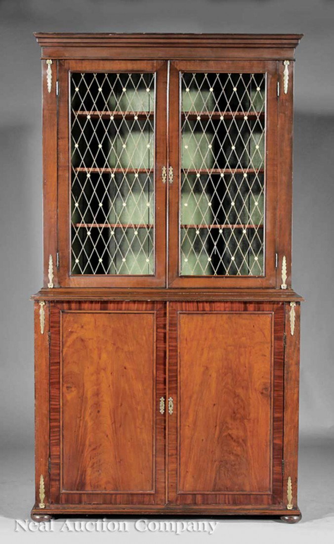 Inlaid and Brass-Mounted Mahogany Bookcase: An Antique Regency-Style Inlaid and Brass-Mounted Mahogany Bookcase, stepped cornice above a pair of cross-bandded doors with later brass lattice panels, lower case with a pair of paneled doors, disc 